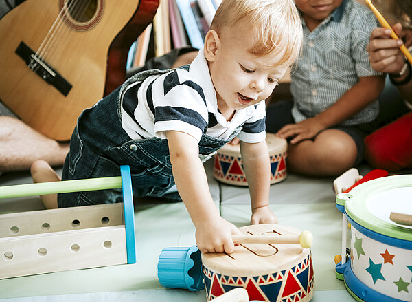 Little kid playing with a wooden drum set